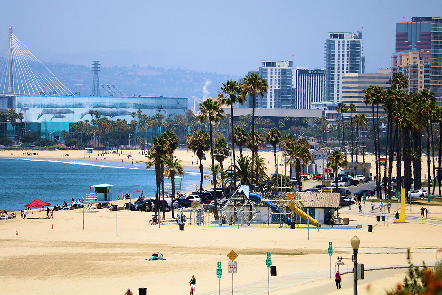 June 6, 2021 in Long Beach, CA:  People on a sandy beach besides the Pacific Ocean and the downtown skyline taken in Long Beach, CA where the public can relax on the beach and swim in the ocean next to the downtown district